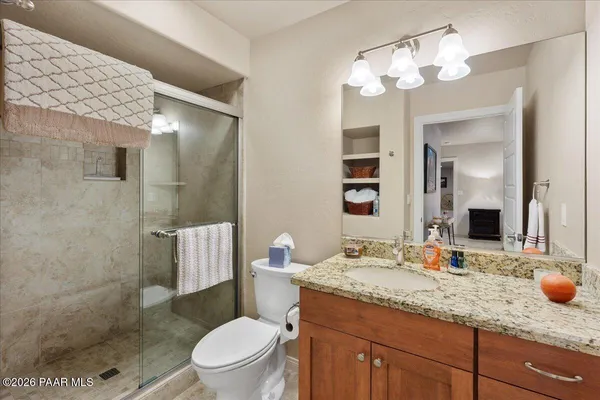 a bathroom with a granite countertop toilet sink and mirror