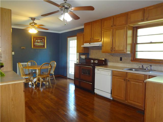 1329 Oak Grove Road Goodspring, TN 38460 - Photo 5 of 20 a kitchen with stainless steel appliances granite countertop a stove top oven a sink dishwasher a dining table and chairs with wooden floor