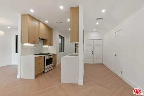 a large kitchen with stainless steel appliances kitchen island granite countertop a refrigerator and a stove top oven