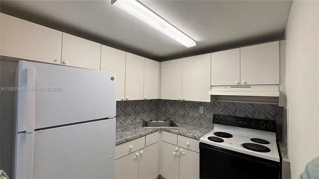 a kitchen with a refrigerator sink stove and cabinets