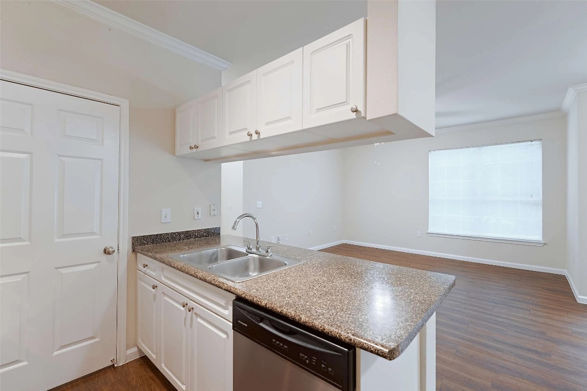10505 South I-35 Frontage Road, Unit 222 Austin, TX 78747 - Photo 9 of 25 a kitchen with granite countertop a sink dishwasher a stove and white cabinets with wooden floor
