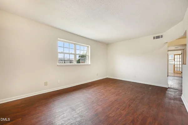 a view of empty room with wooden floor and electronic appliances