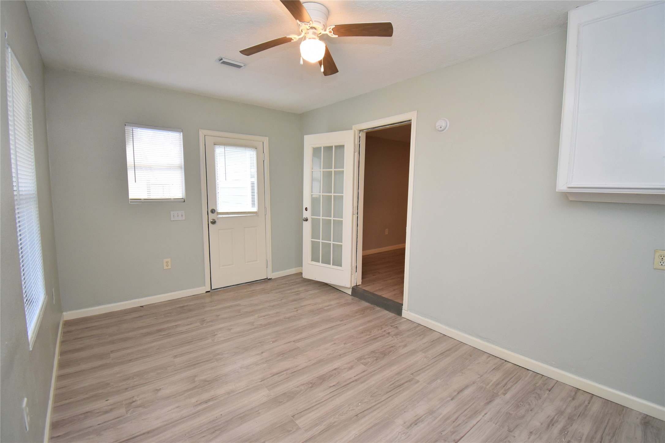 1115 Georgina Street Rosenberg, TX 77471 - Photo 15 of 17 an empty room with wooden floor chandelier fan and windows