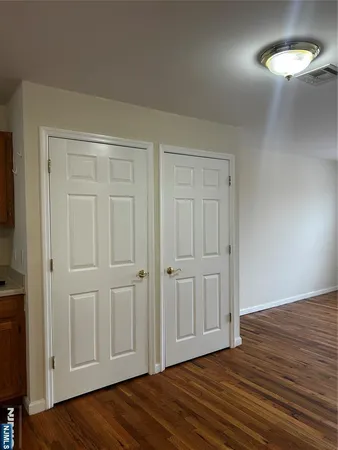 an empty room with wooden floor closet and windows