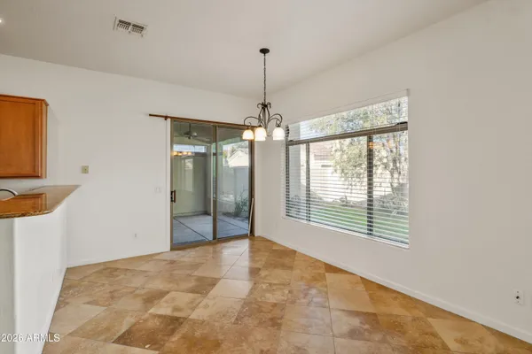 a view of an empty room with chandelier fan and windows