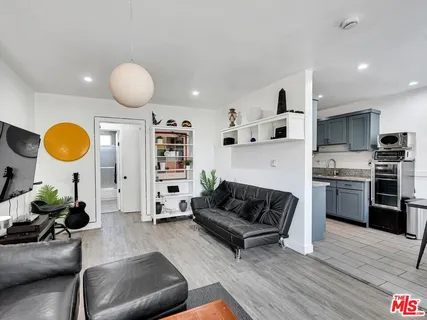 a living room with furniture a flat screen tv and kitchen view