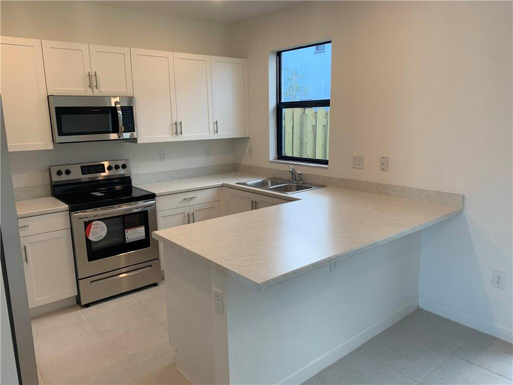 28706 Southwest 133rd Court Homestead, FL 33033 - Photo 4 of 40 a kitchen with granite countertop a sink a stove and microwave with cabinets