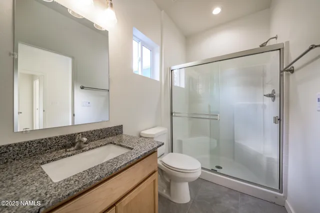 a bathroom with a granite countertop sink toilet and shower