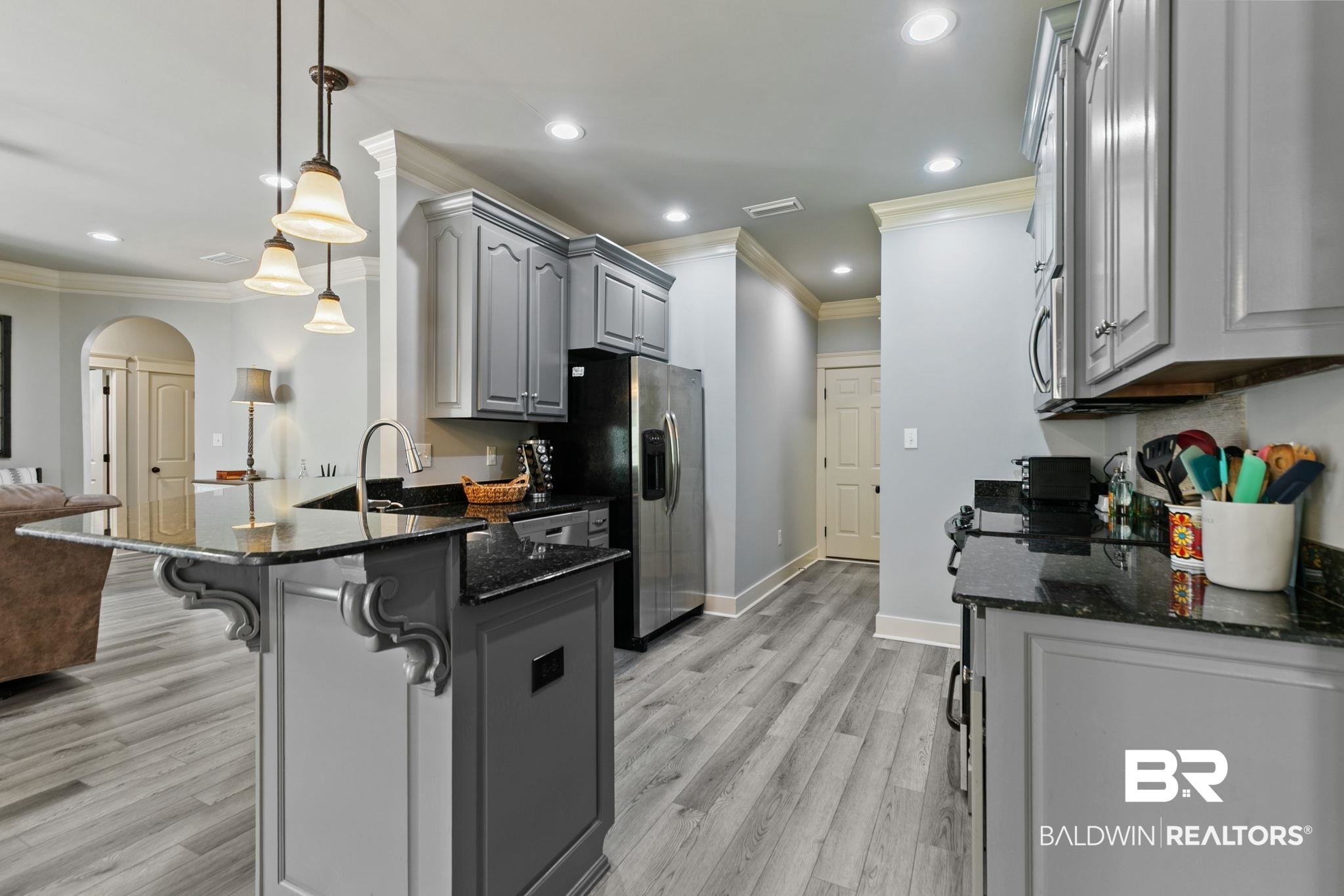 9584 Sanibel Loop Daphne, AL 36526 - Photo 47 of 48 Kitchen with arched walkways, dark stone counters, open floor plan, gray cabinets, and a kitchen breakfast bar