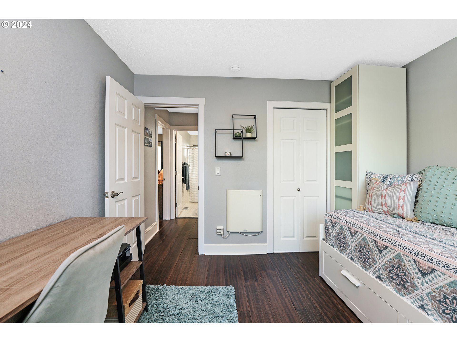 7702 Southwest Barnes Road, Unit D Portland, OR 97225 - Photo 13 of 24 a bedroom with a bed and wooden floor