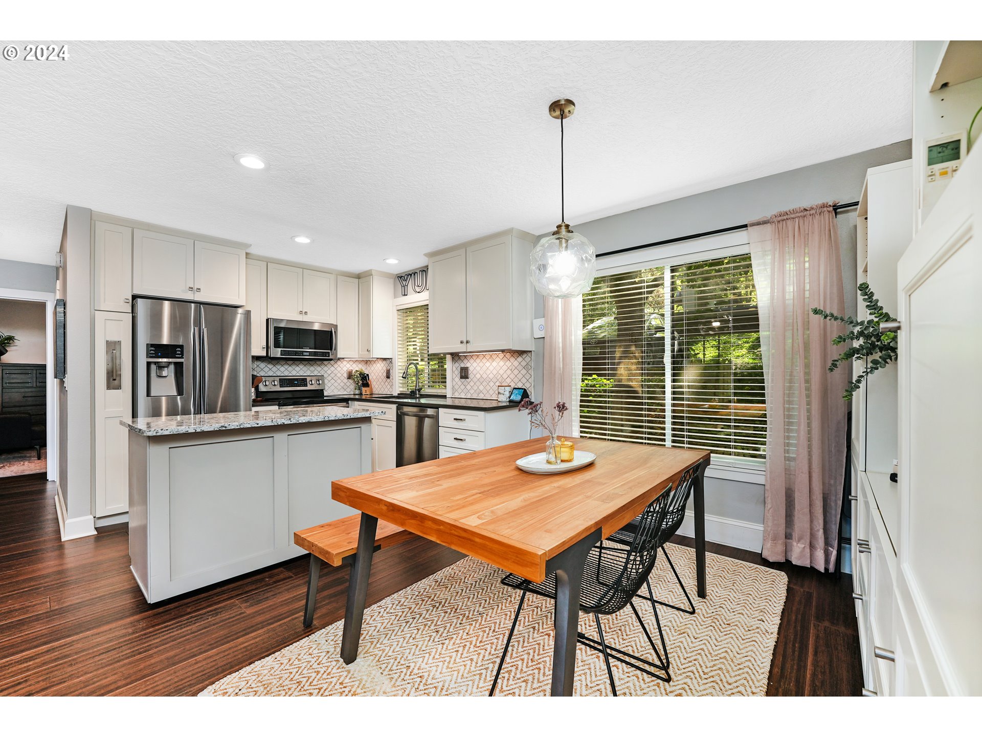 7702 Southwest Barnes Road, Unit D Portland, OR 97225 - Photo 4 of 24 a open kitchen with stainless steel appliances kitchen island granite countertop a dining table chairs and granite counter tops