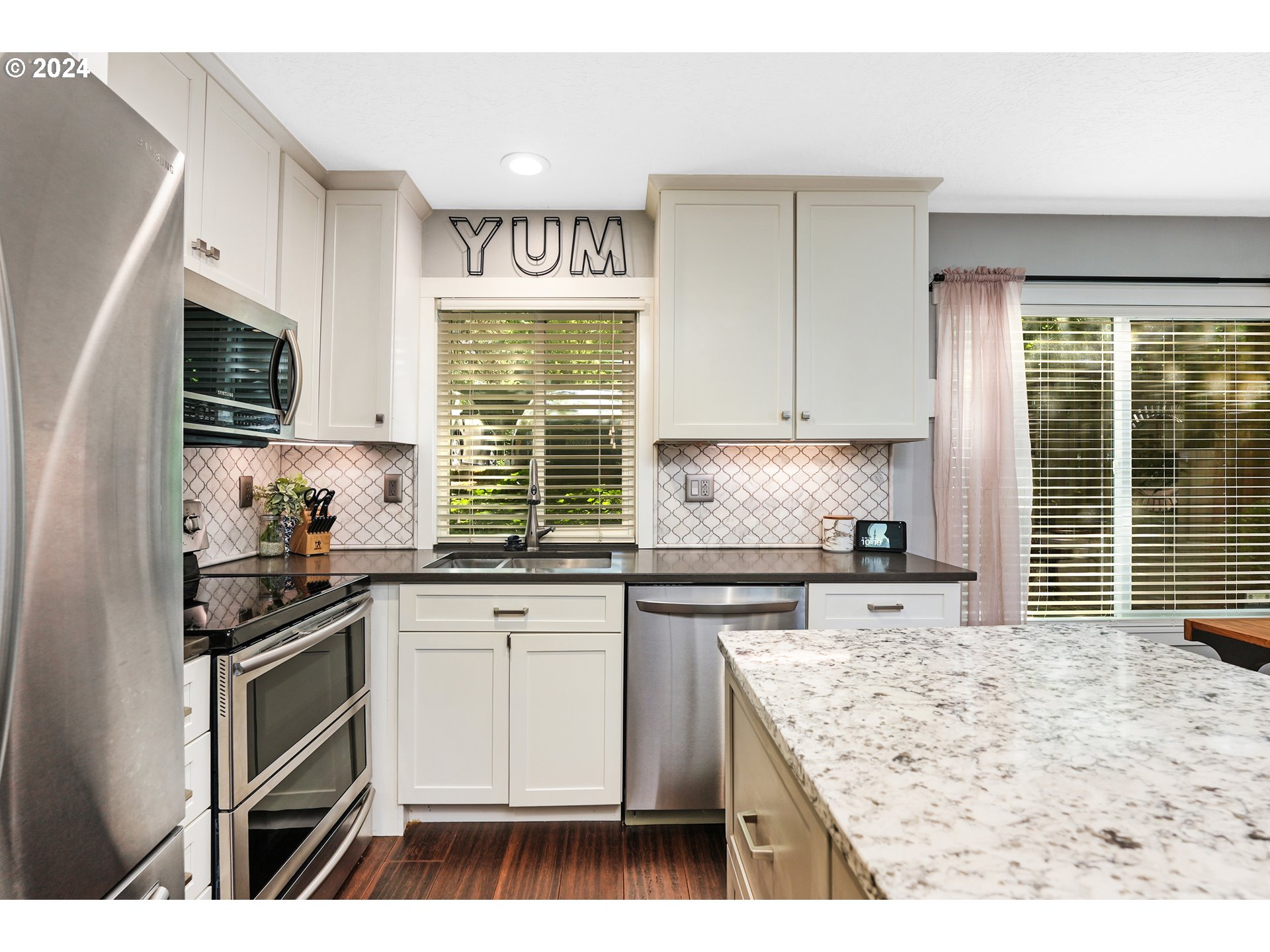 7702 Southwest Barnes Road, Unit D Portland, OR 97225 - Photo 6 of 24 a kitchen with stainless steel appliances kitchen island granite countertop a stove a sink and a microwave