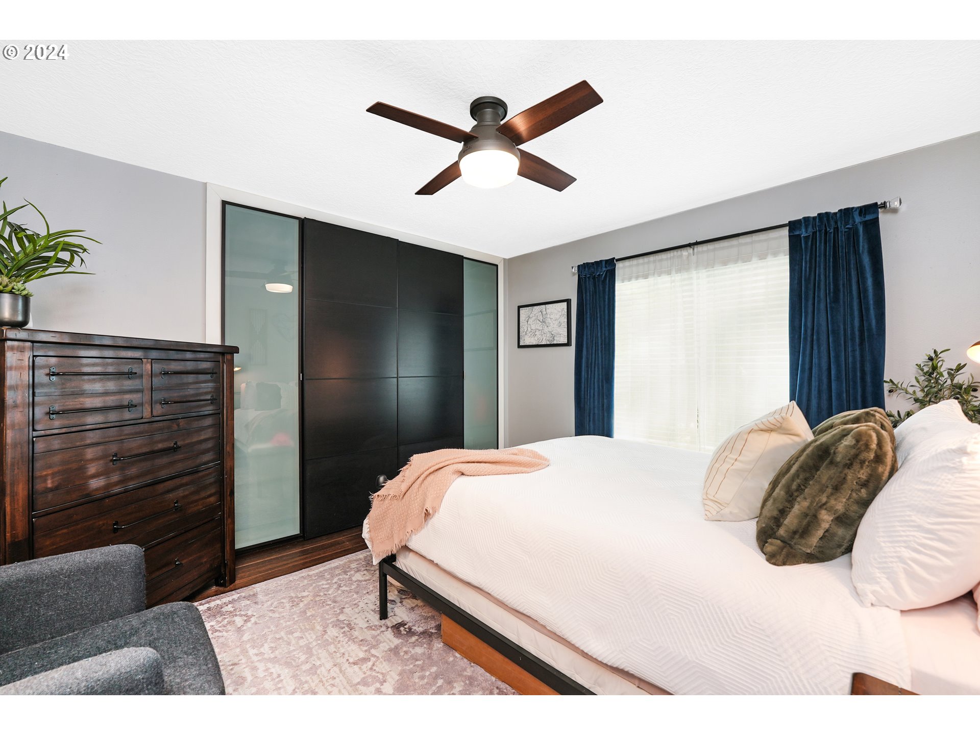 7702 Southwest Barnes Road, Unit D Portland, OR 97225 - Photo 9 of 24 a bedroom with a bed and a ceiling fan