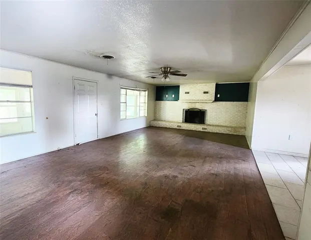 an empty room with windows and fireplace