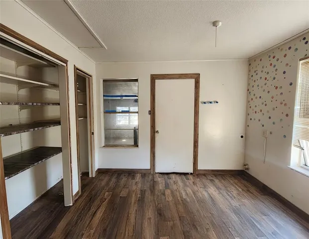 a view of empty room with wooden floor and windows