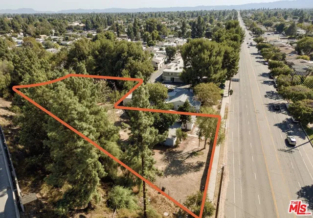 an aerial view of a residential houses with outdoor space and trees