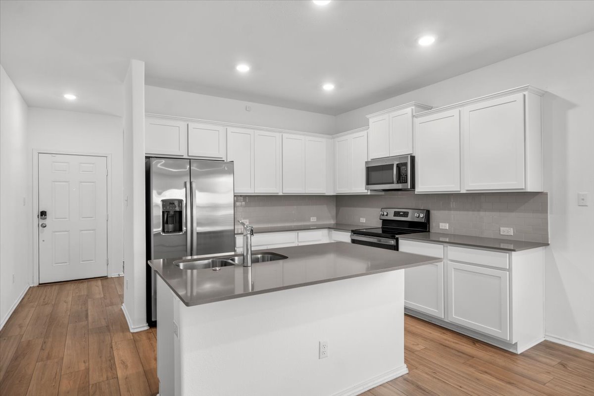 448 Perfect World Loop Jarrell, TX 76537 - Photo 14 of 40 A sleek island with a sink anchors this bright kitchen, complete with modern appliances and ample white cabinetry.