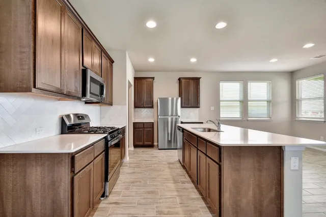 a large kitchen with stainless steel appliances granite countertop plenty wooden cabinets counter space and a sink