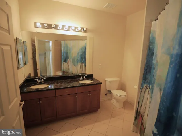 a bathroom with a granite countertop sink toilet and mirror