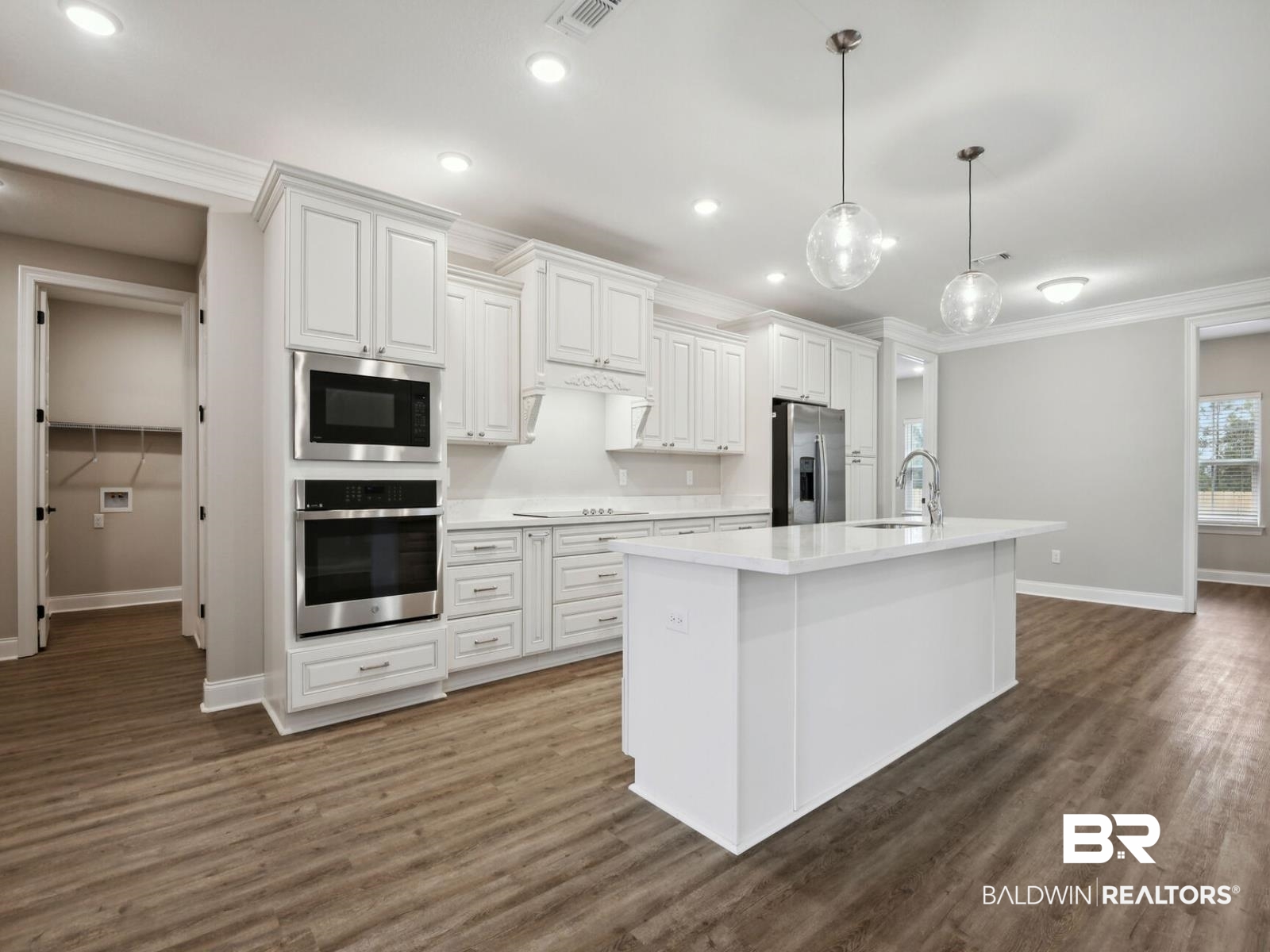 12942 Gondala Street Elberta, AL 36530 - Photo 5 of 18 Kitchen with stainless steel appliances, ornamental molding, pendant lighting, white cabinets, and dark wood-style flooring