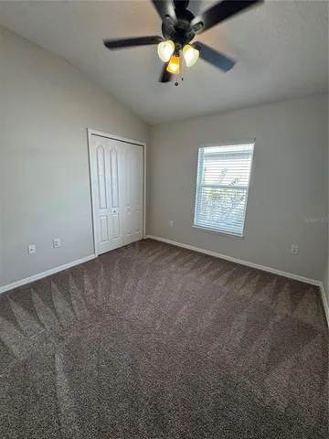 an empty room with a window and a ceiling fan
