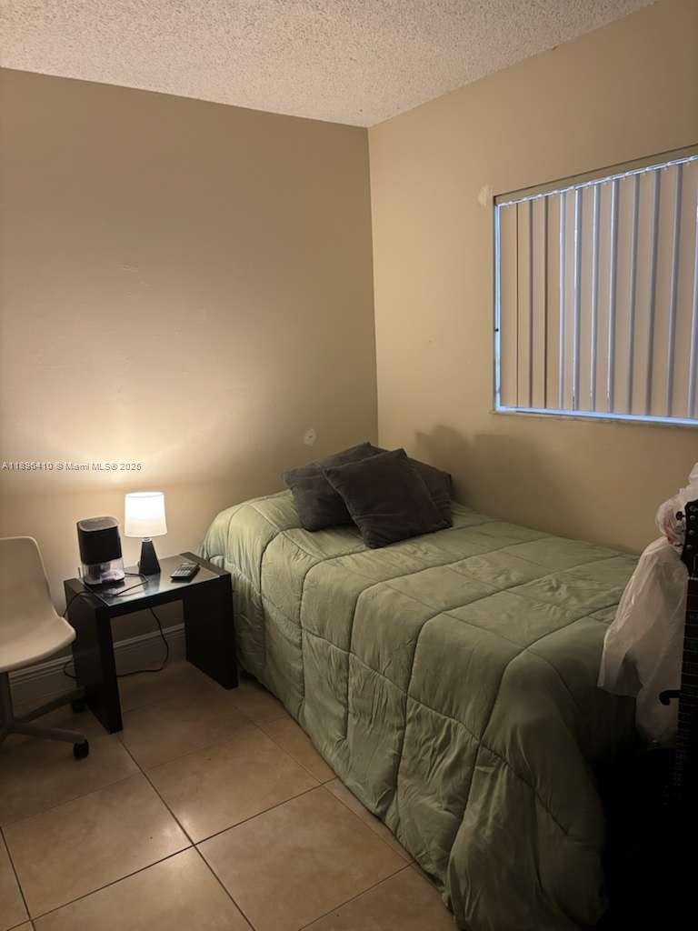 8400 Southwest 133rd Avenue Road, Unit 202 Miami, FL 33183 - Photo 15 of 23 a bedroom with a bed and a lamp on dresser