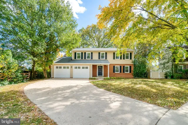 a front view of a house with a garden and trees