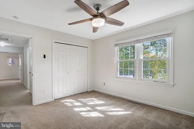 an empty room with windows and fan