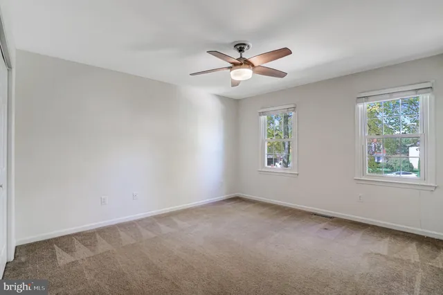 an empty room with a ceiling fan and a window