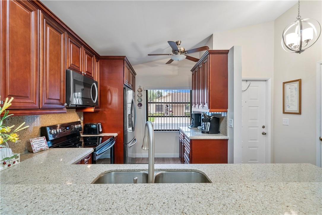 8046 Summerview Terrace Boca Raton, FL 33496 - Photo 6 of 25 a kitchen with stainless steel appliances granite countertop a sink stove and refrigerator