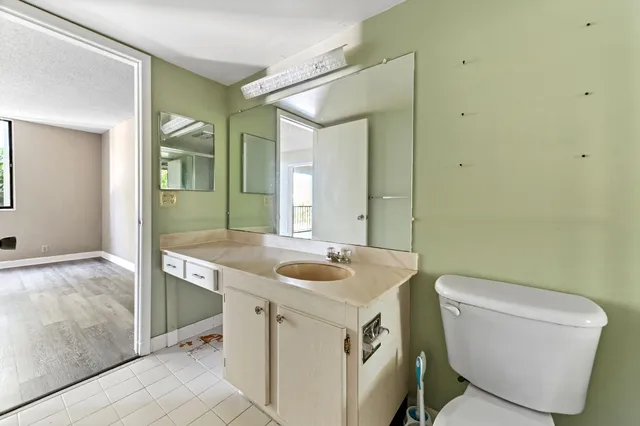 a bathroom with a granite countertop toilet a sink and a mirror
