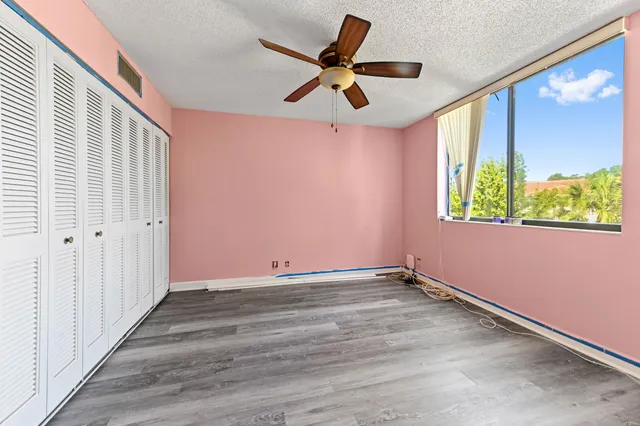 an empty room with wooden floor fan and windows
