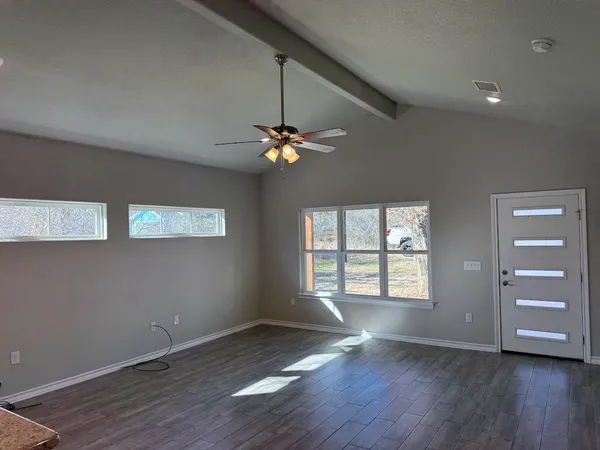 an empty room with wooden floor chandelier and windows
