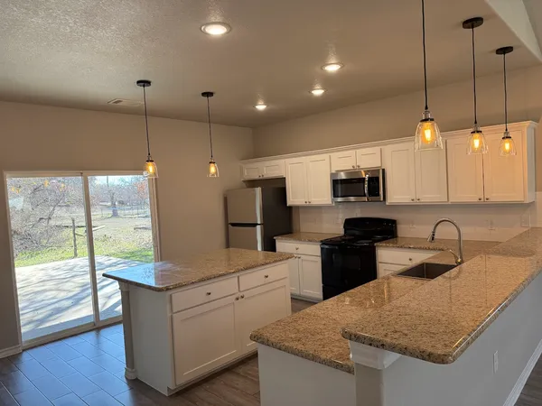 a kitchen with kitchen island granite countertop a sink a counter top space appliances and cabinets
