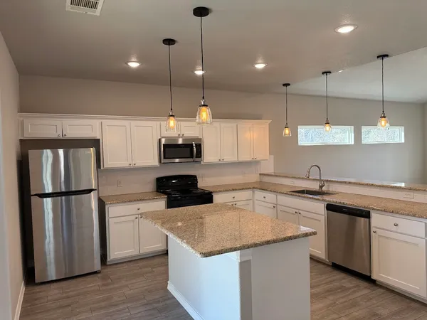 a kitchen with a refrigerator a sink and wooden floor