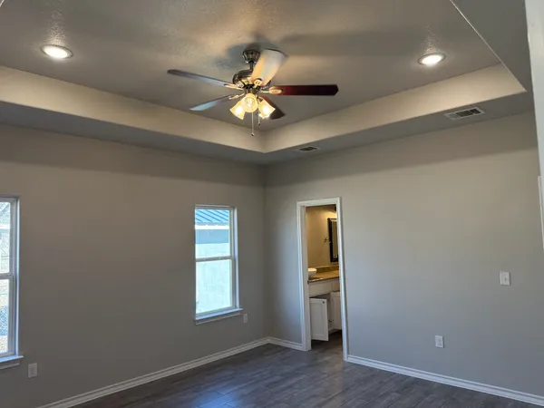 a view of an empty room with a window and wooden floor
