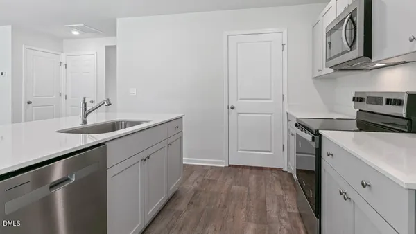 a kitchen with a sink dishwasher a stove and a refrigerator with wooden floor
