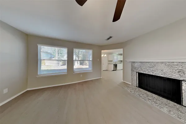 an empty room with windows and fireplace