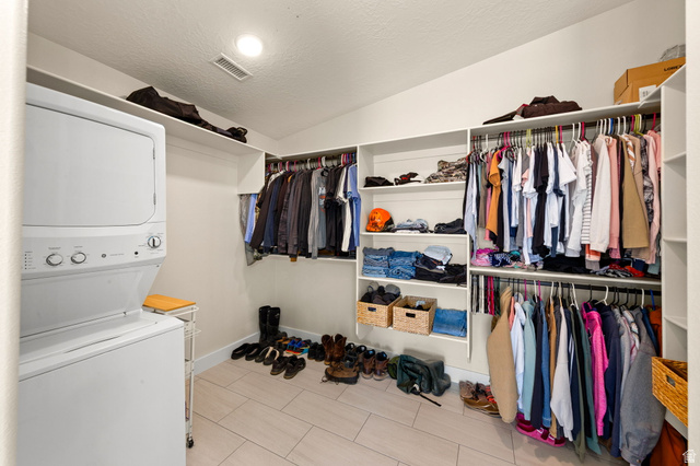 2591 East Washington Dam Road Washington, UT 84780 - Photo 25 of 67 Integrated laundry closet with stacked appliances, featuring an organized walk-in closet with extensive built-in shelving, multiple hanging rods, and light wood-finish flooring