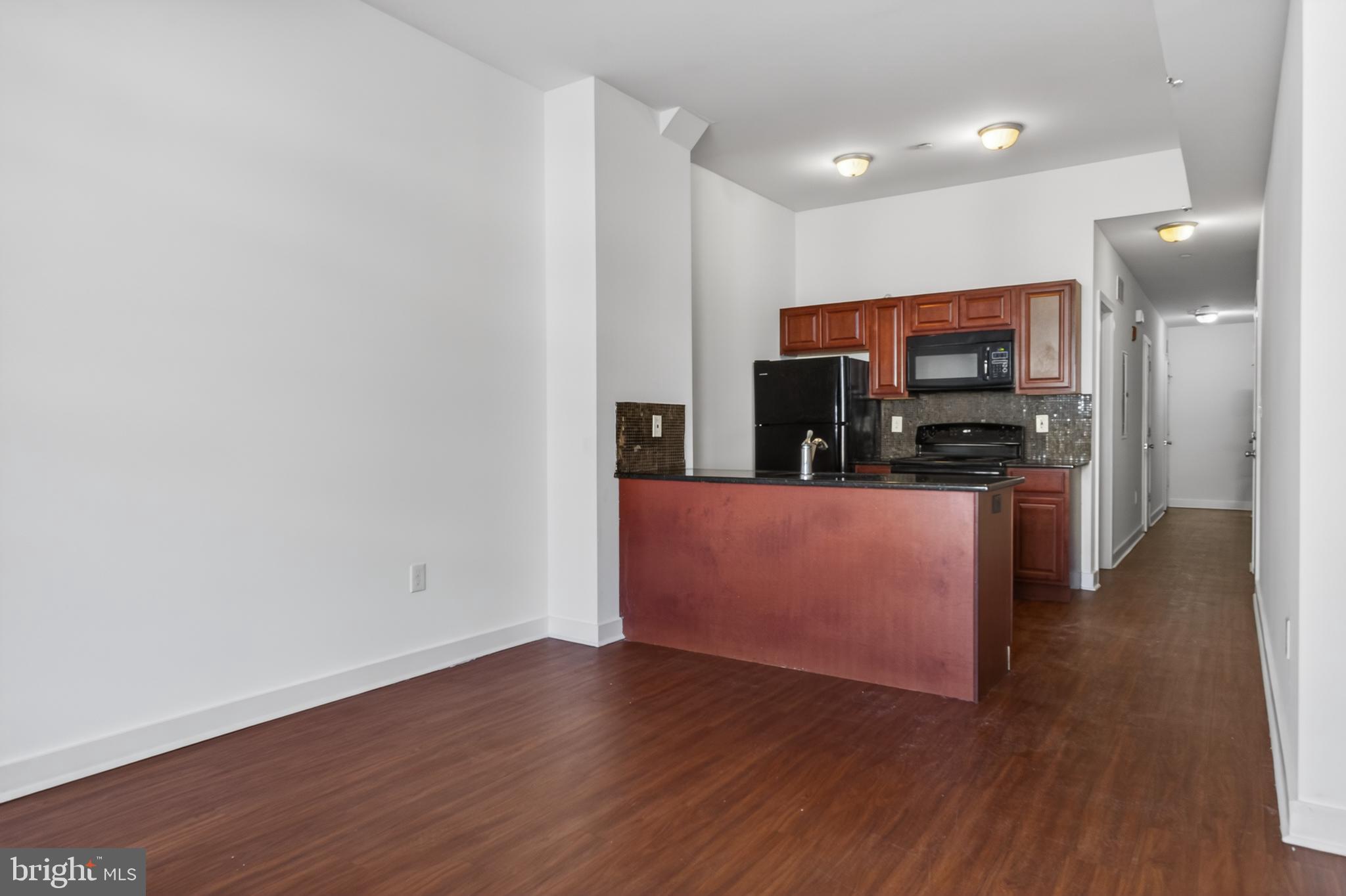 6040 Market Street, Unit 2 Philadelphia, PA 19139 - Photo 1 of 16 a kitchen with stainless steel appliances a microwave a stove and a wooden floors