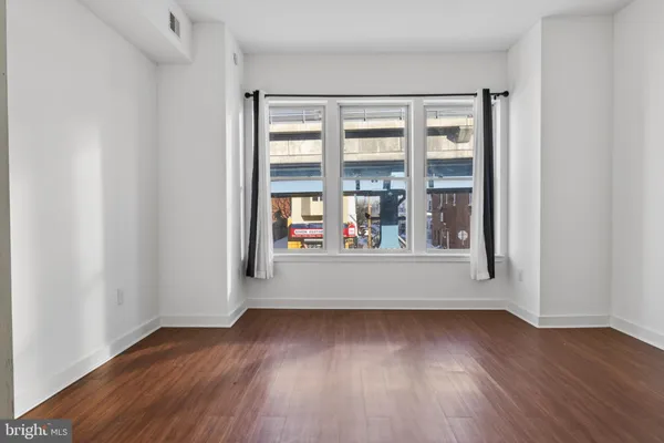 an empty room with wooden floor and large window