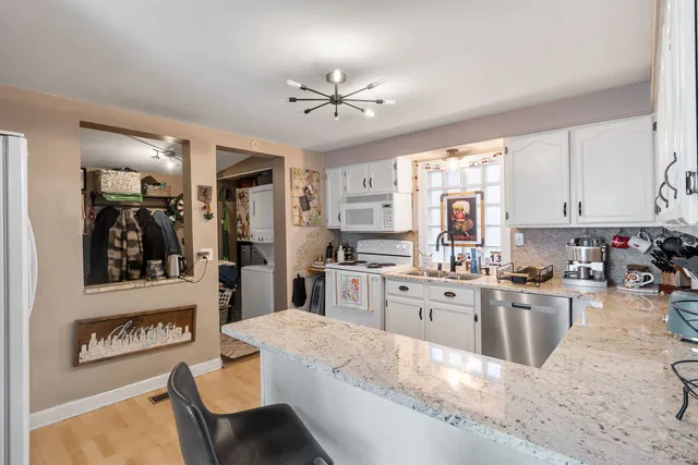a large white kitchen with cabinets a sink a window and stainless steel appliances