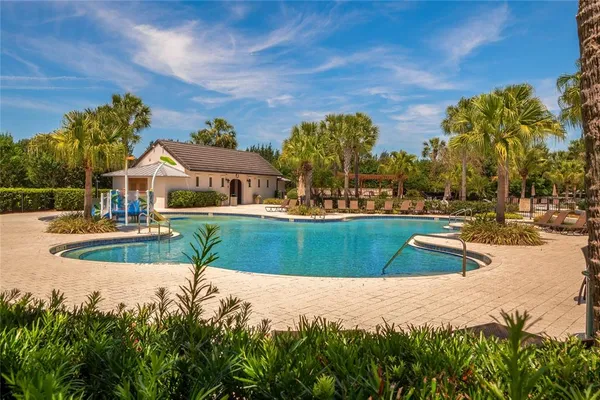 a view of swimming pool with outdoor seating and trees in the background
