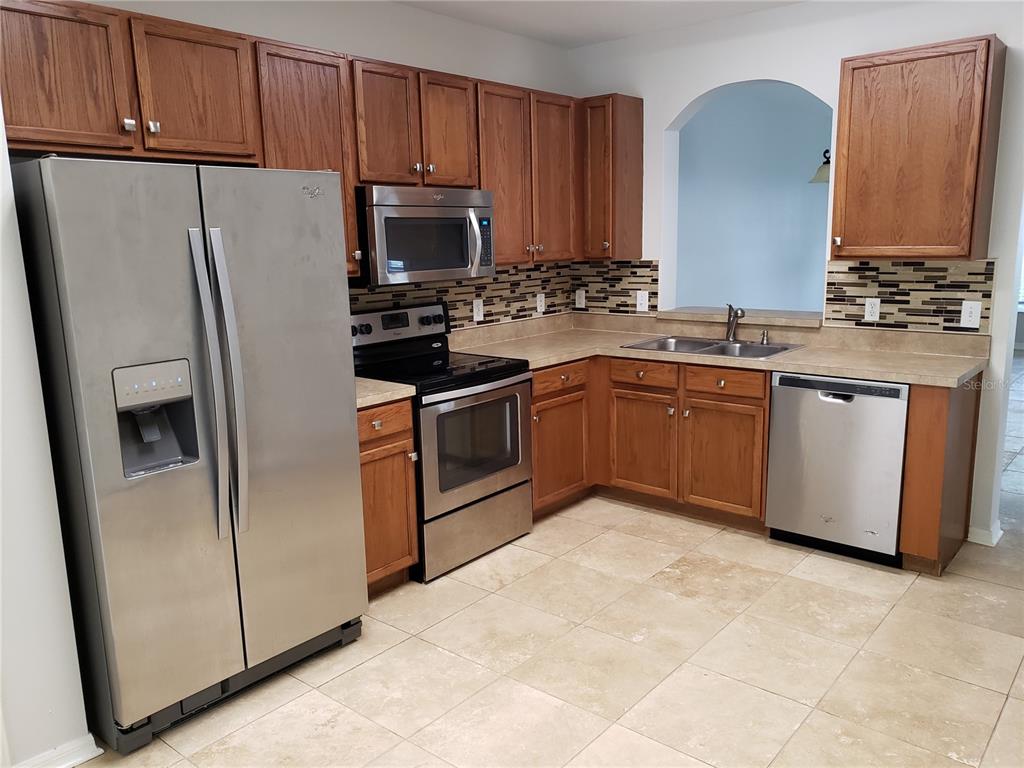 5870 Fishhawk Ridge Drive Lithia, FL 33547 - Photo 10 of 34 a kitchen with stainless steel appliances granite countertop a refrigerator stove a sink and a microwave