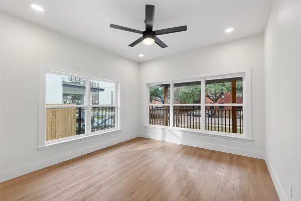 a view of an empty room with a window and wooden floor