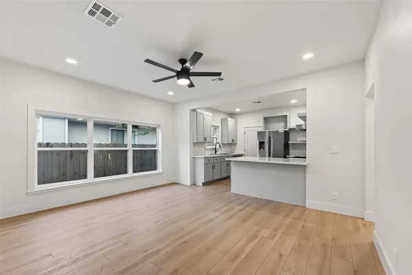 a view of a kitchen with stainless steel appliances a sink and wooden floor