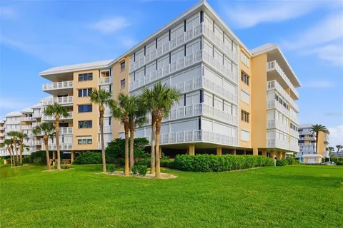 a room with lots of white furniture a chandelier and a dining table