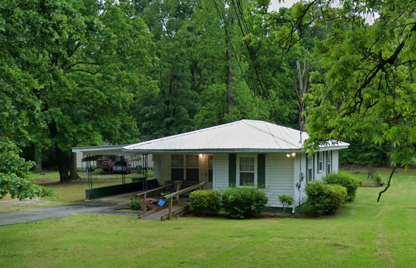 a view of house with garden and tall trees
