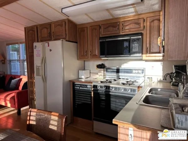 a kitchen with stainless steel appliances granite countertop a stove refrigerator sink and microwave