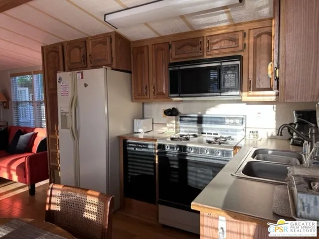 a kitchen with stainless steel appliances granite countertop a stove refrigerator sink and microwave